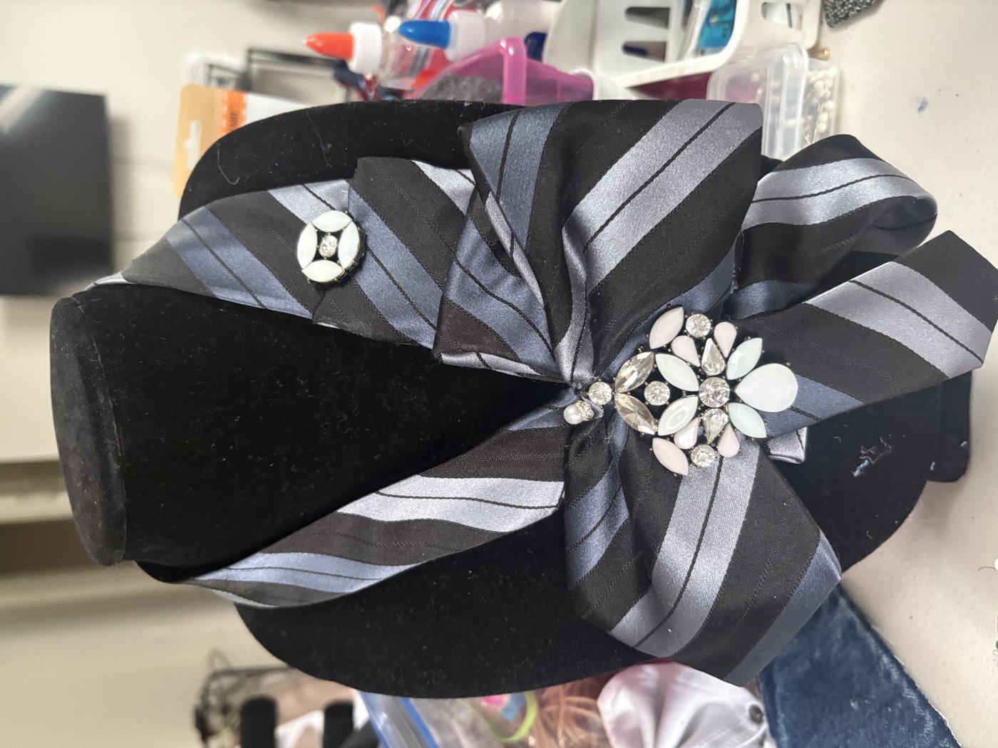 Grey striped necktie knotted into a collar with two brooches, a button and a crystal flower.