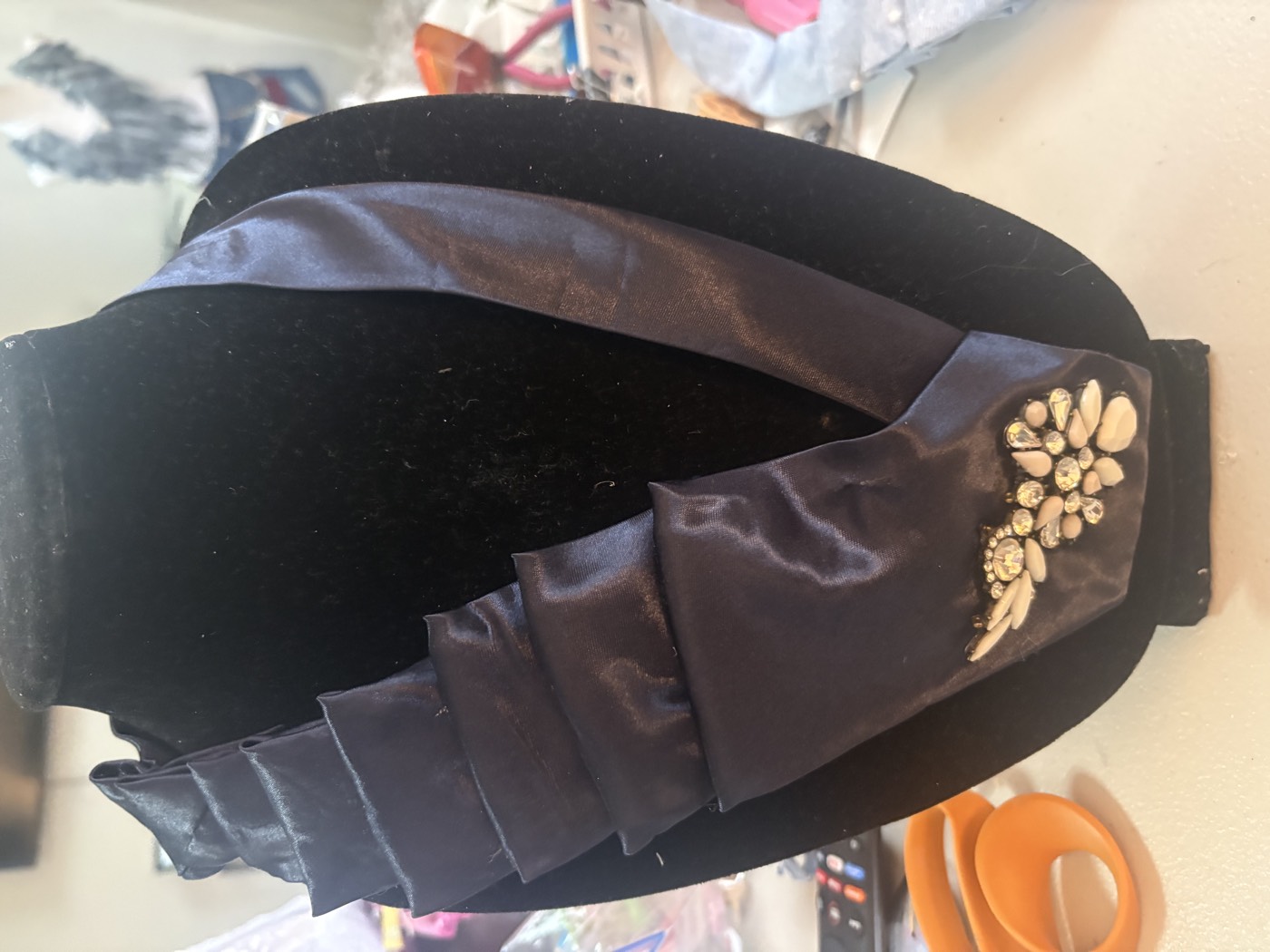 Charcoal satin necktie pleated into a fan with a small crystal floral brooch at the point.