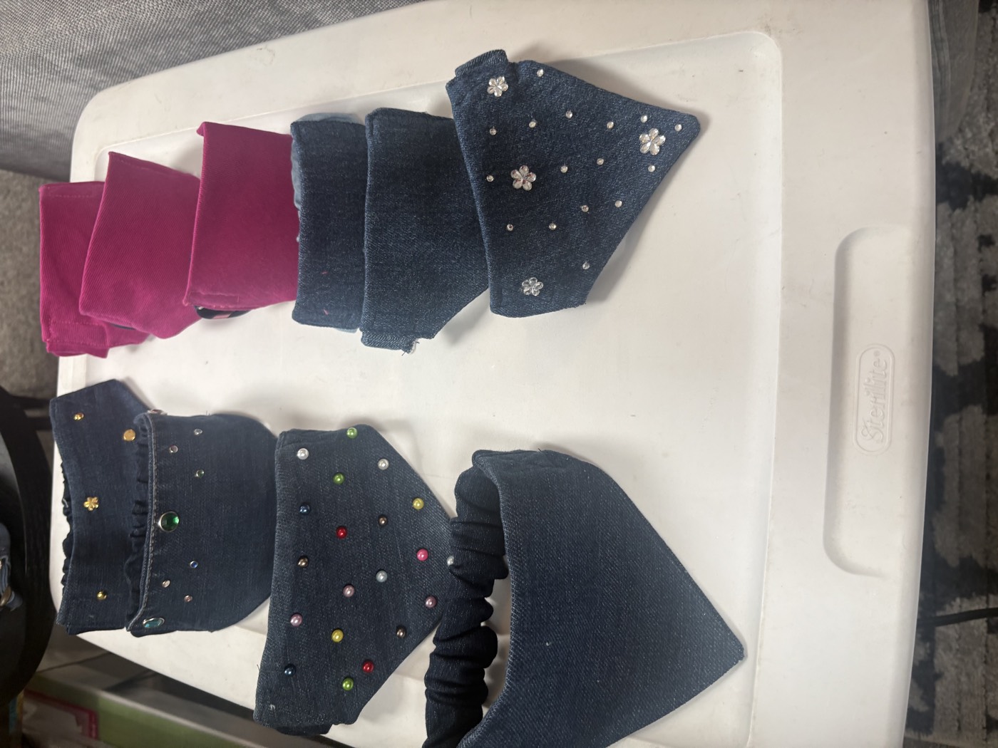 A tray of small denim and magenta bandanas, some studded with colorful rhinestones.
