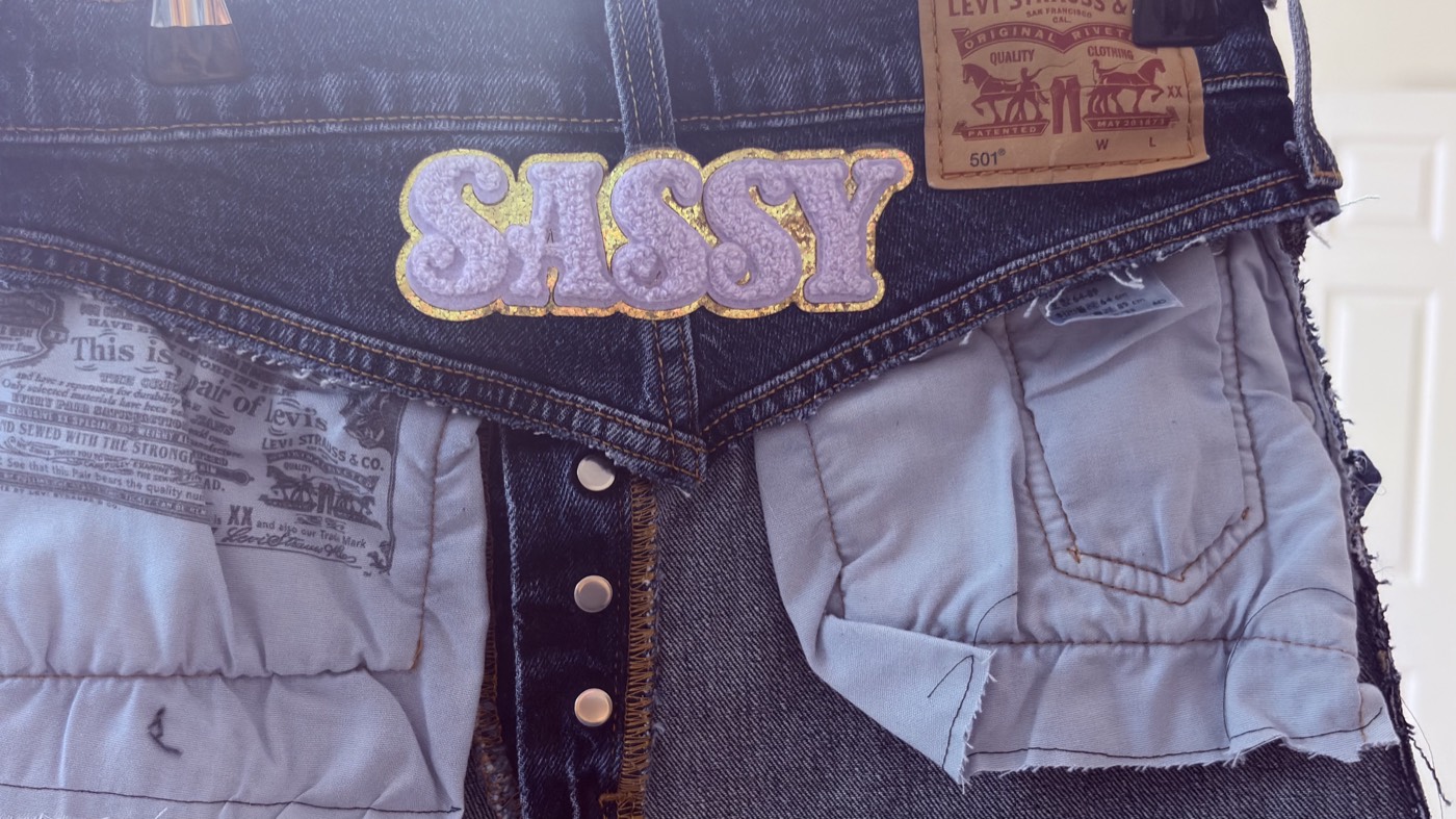 The back of a pocket belt: a Levi's waistband turned inside out with a purple SASSY chenille patch and frayed pocket bags.